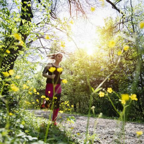 ung sporty kvinne jogger gjennom skogen