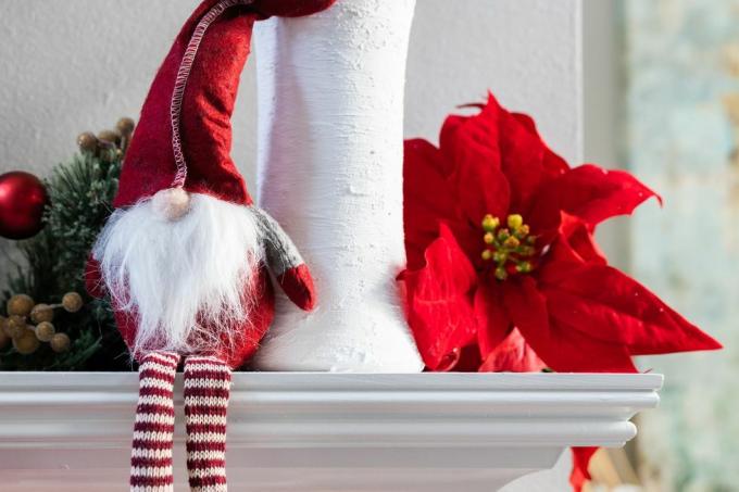 en klassisk norsk julenissedekorasjon som sitter på en hvit moderne mantel med en hvit vase med eukalyptus og en julestjerneblomst