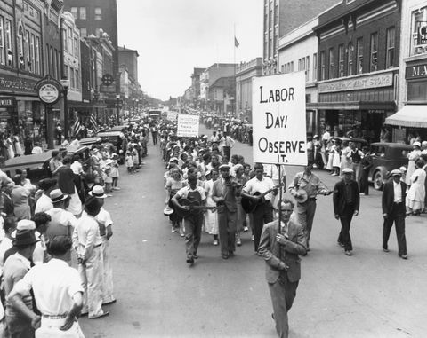 arbeidsdagsparade i 1934 med folk som gikk i gata mens de holdt skilt mens en mengde så på fra fortauene