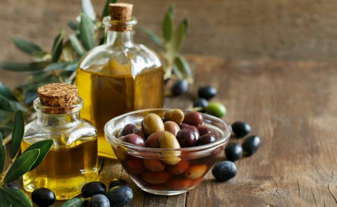 Olivenolje og oliven på trebakgrunn