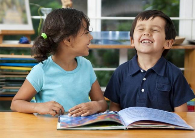 to leende barn koser seg med en bok på skolen