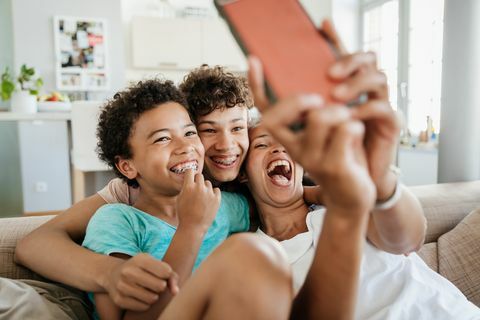 en alenemor som moret seg med sine to sønner hjemme, og sitter i sofaen og tok selfies på smarttelefonen sin