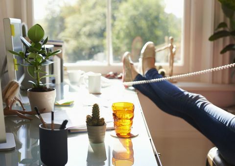 Kvinne som snakker på telefon på hjemmekontor - bare føttene og beina vist