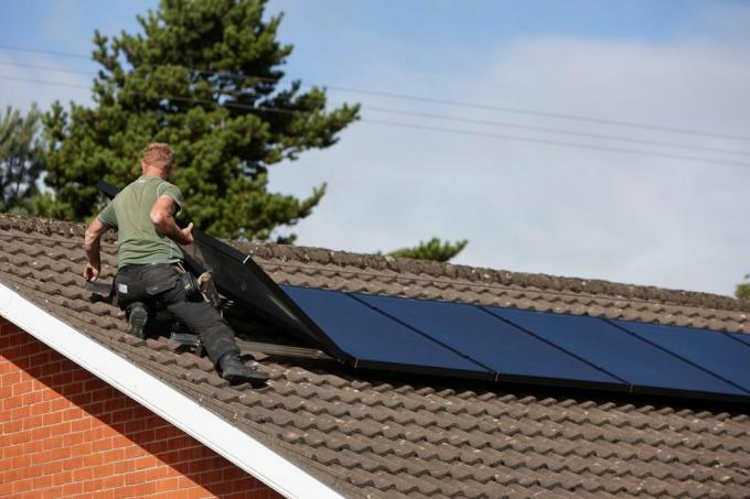 h0chn1 mann installerer solcellepaneler på taket i en innenlandsk solcelleinstallasjon i Storbritannia