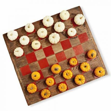 et treplate malt som et brikkespill med minigresskar i hvitt og oransje som lekestykkene