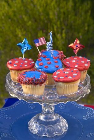 seks røde eller blå dekorerte cupcakes på et kuttet stativ av glasskake