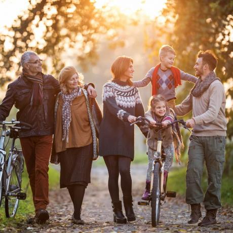 smilende flergenerasjonsfamilie som tar en tur med sykler i naturen og nyter tiden sammen