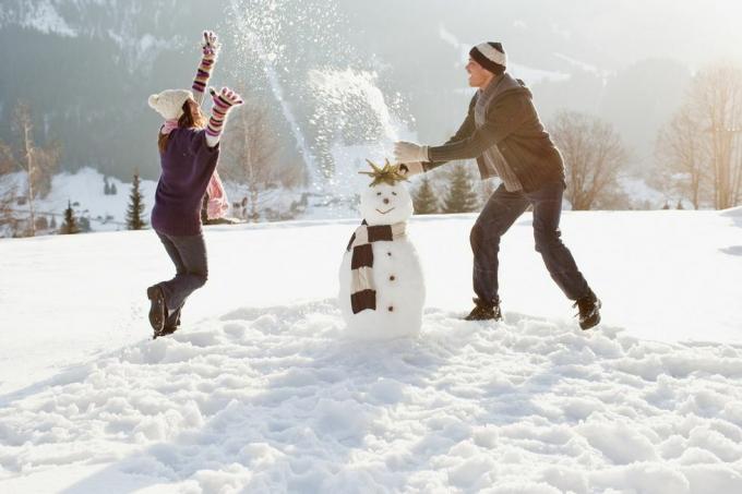 par som lager snømann og leker i snø