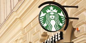 Wien, Østerrike 1. mai 2012 grønn Starbucks kaffe-logo på en stang og Starbucks-kaffetekst på fasaden til et gammelt hus i Wien sentrum diagonalt fotografert fokus på logo starbucks er kjent for store å gå kaffe