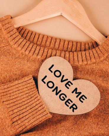 slow fashion konsept oransje strikket genser på beige bakgrunn bevisst og miljøvennlig forbruk moderne trender i shopping null avfall selektiv fokus