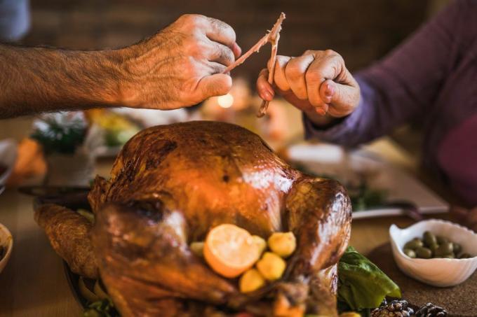 nærbilde av ugjenkjennelige mennesker som trekker bærearm under Thanksgiving middag ved spisebordet