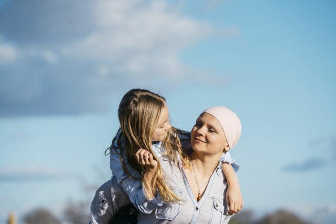 kvinne sett fra hake til mage som holder ut hendene for å lage en hjerteform for å ramme inn et rosa bånd på den hvite genseren hennes