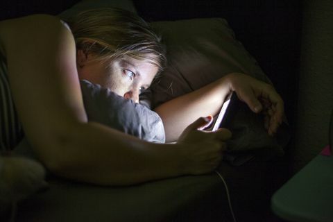 Kvinne som ser på smart telefon i sengen