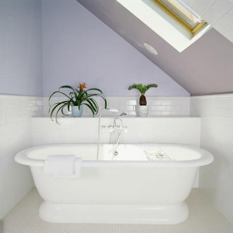 badekar under takvindu på loftsbad med lilla lilla vegger