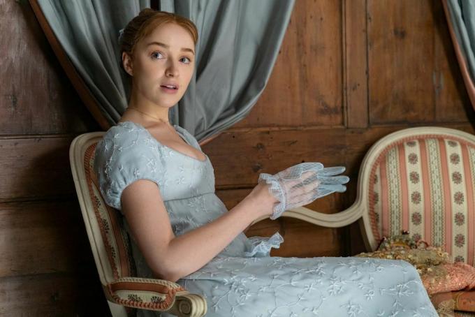 phoebe dynevor som daphne bridgerton i episode 102, sittende, iført en blå, empire midjet kjole