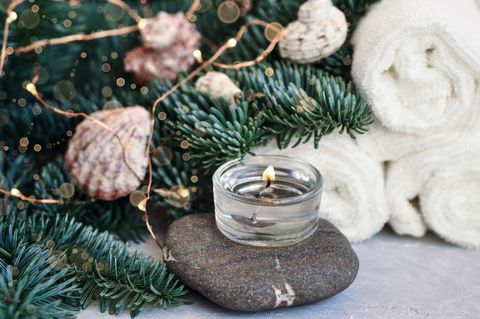 jule- og nyttårskort med grangrener dekorert med baller, lys, skjell og steiner for spabehandlinger på et skjønnhetskonsept med grå bakgrunn