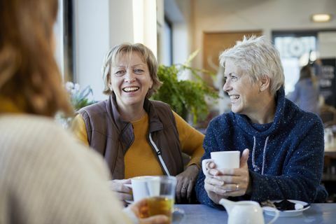 lesbisk par og voksen datter drikker kaffe og snakker på kafé