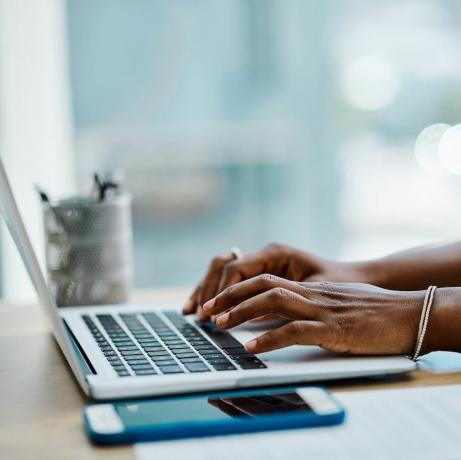 nærbilde av en svart forretningskvinne som skriver på et bærbart tastatur på et kontor alene