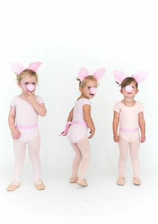 små jenter i rosa strømpebukser og onesies med griseører og grise snuter