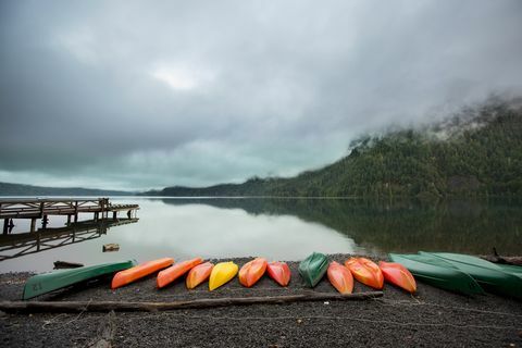 en serie fargerike kanoer langs bredden av en innsjø