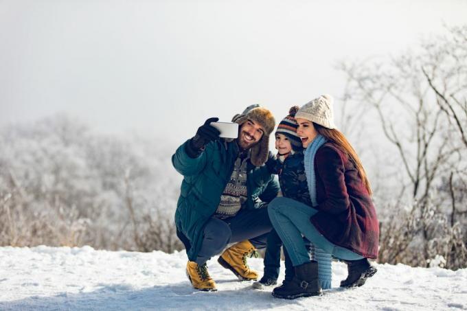 familie tar selfie på vinterdag i den snødekte skogen