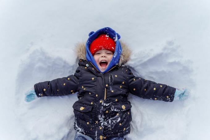 ungt barn i snøen gjør snøengel