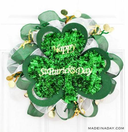 krans laget av grønt tinsel, bånd, burlap og mer formet som en klaver, med gullbokstaver som leser glad St. Patrick's Day