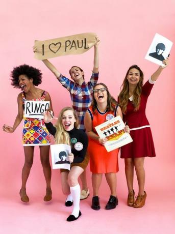 fem kvinner kledd som beatlemaniacs i vintageklær som ler og roper, en holder på beatles-albumet