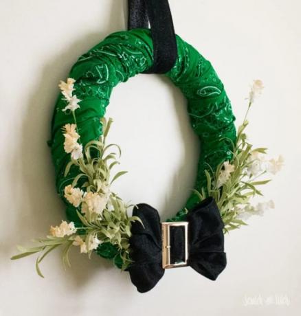 grønn krans laget av bandanas med en svart sløyfe med en gullspenne nederst, det er løvete faux løvverk som stikker ut av baugen